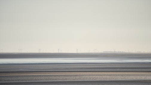 View across the estuary at low tide. There are wind turbines in the distance.